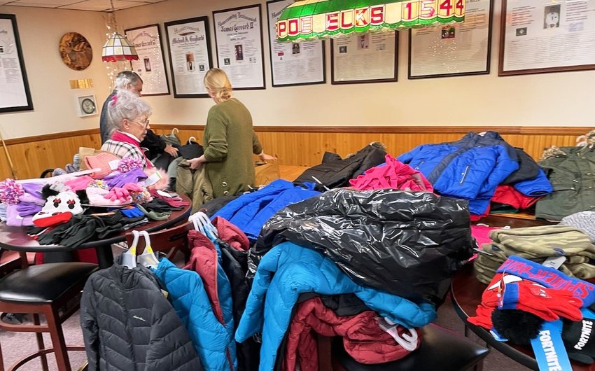 Past Elks exalted ruler Ronni Scannell, foreground, current exalted ruler Mike Brennan and Maggie Sheerer, chair of the Queen of Hearts, sort donated winter coats.